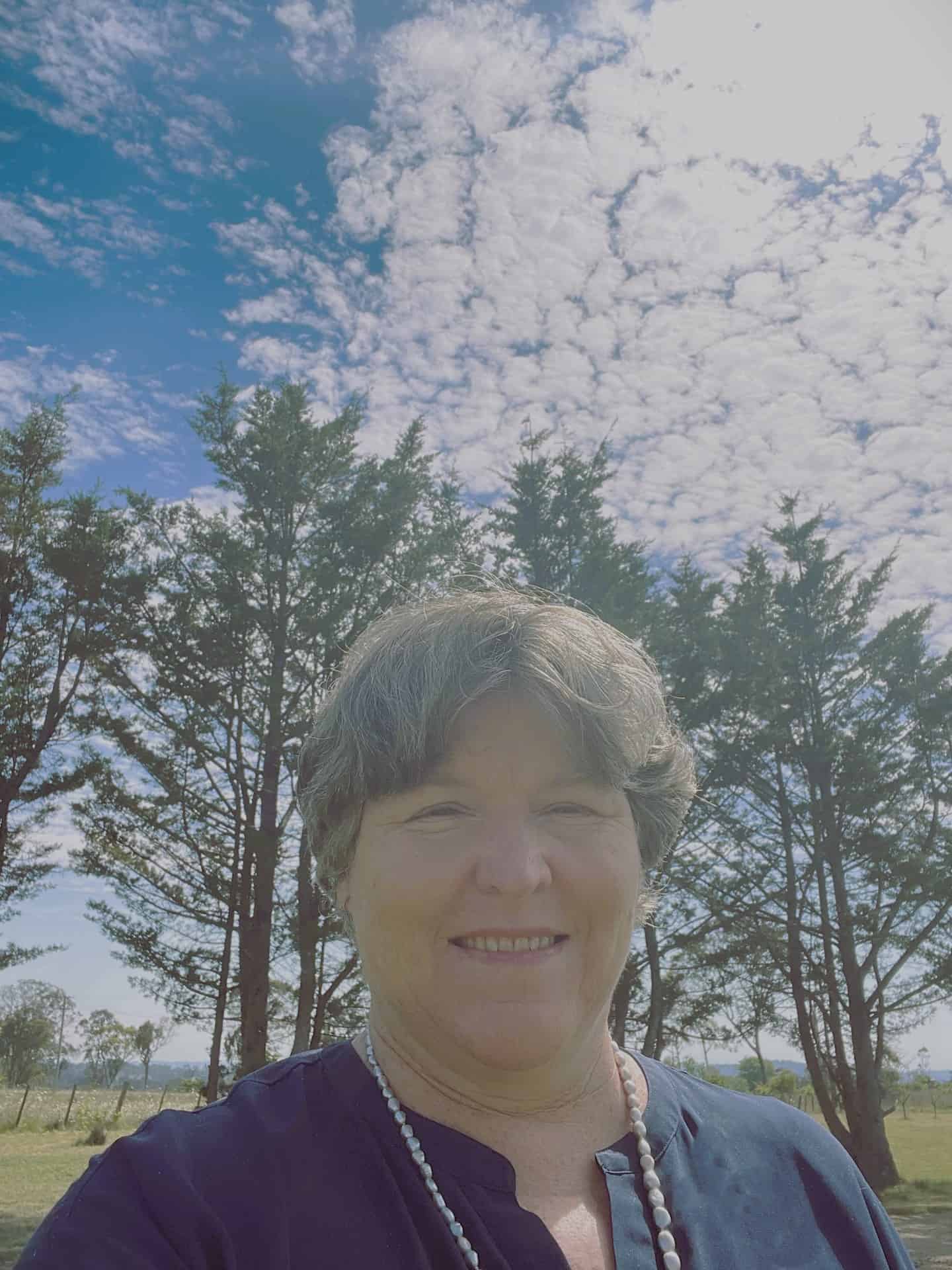 Woman smiling outside with trees in the background