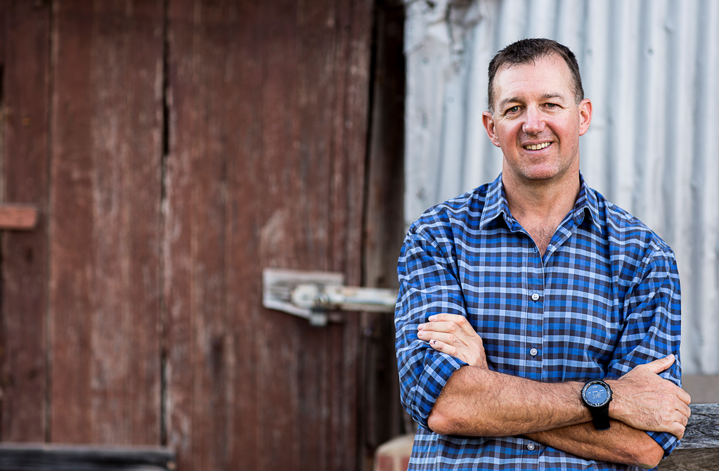 Man smiling at camera in front of shed