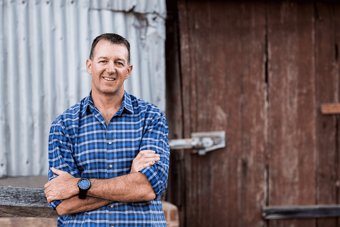 Man smiling at camera in front of shed