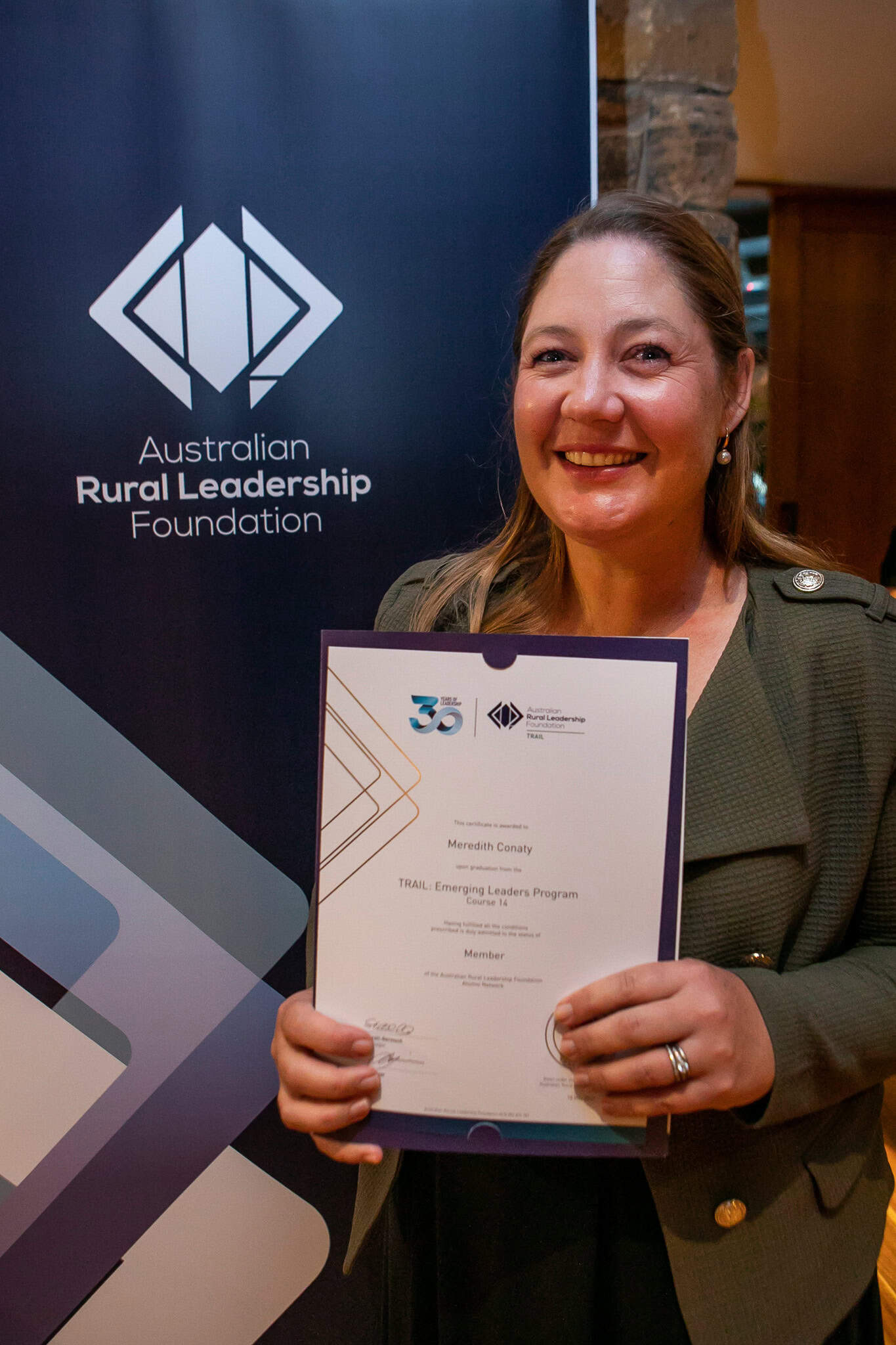Woman smiling holding up graduation certificate