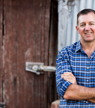 Man smiling at camera in front of shed