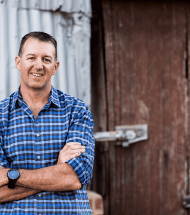 Man smiling at camera in front of shed